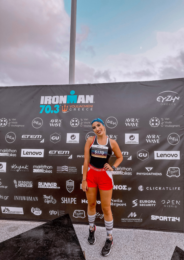 A woman standing in front of a banner for ironman triathlon.