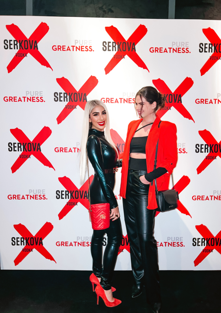 Two women standing next to each other on a red carpet.